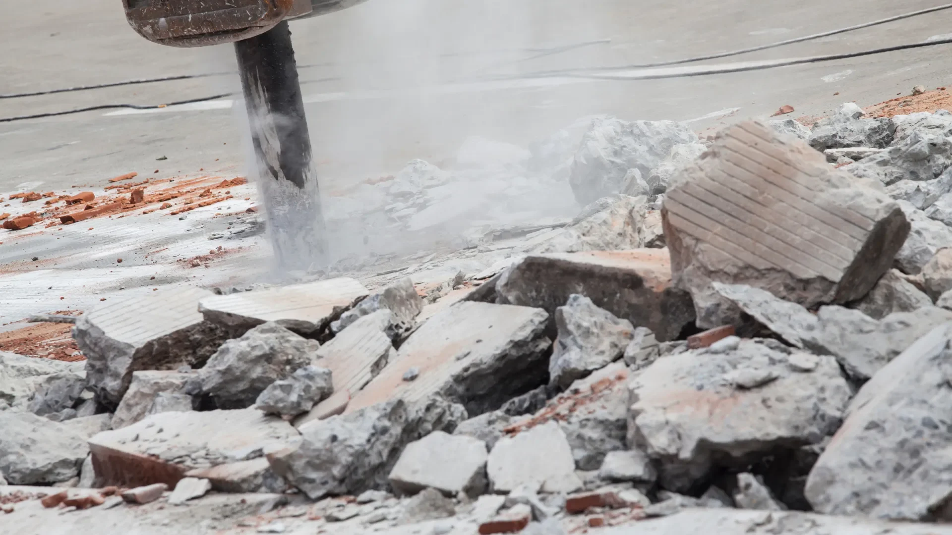 Hydraulic breaker creating dust while removing concrete and brick