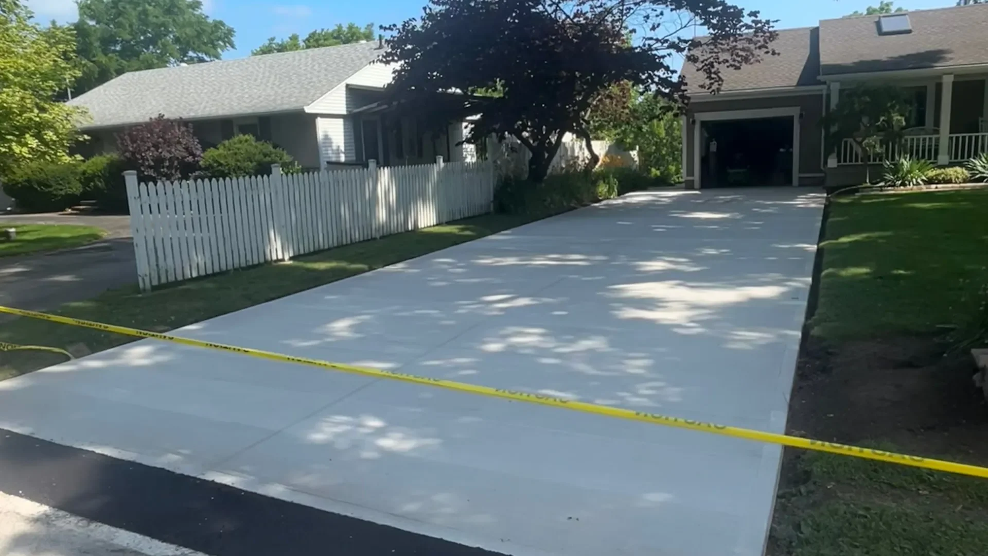 Newly installed broom-finish concrete driveway with caution tape in Lincoln
