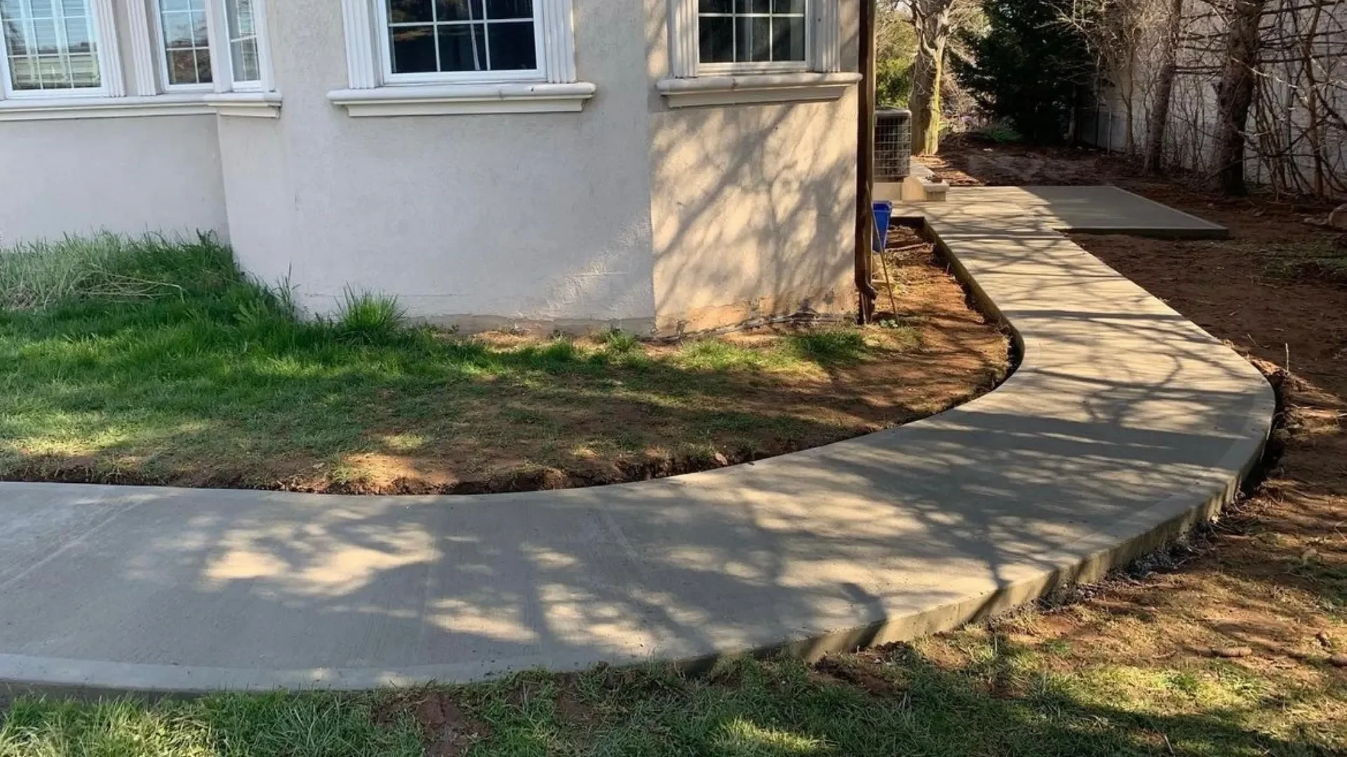 Curved concrete walkway and patio path along a Grimsby home