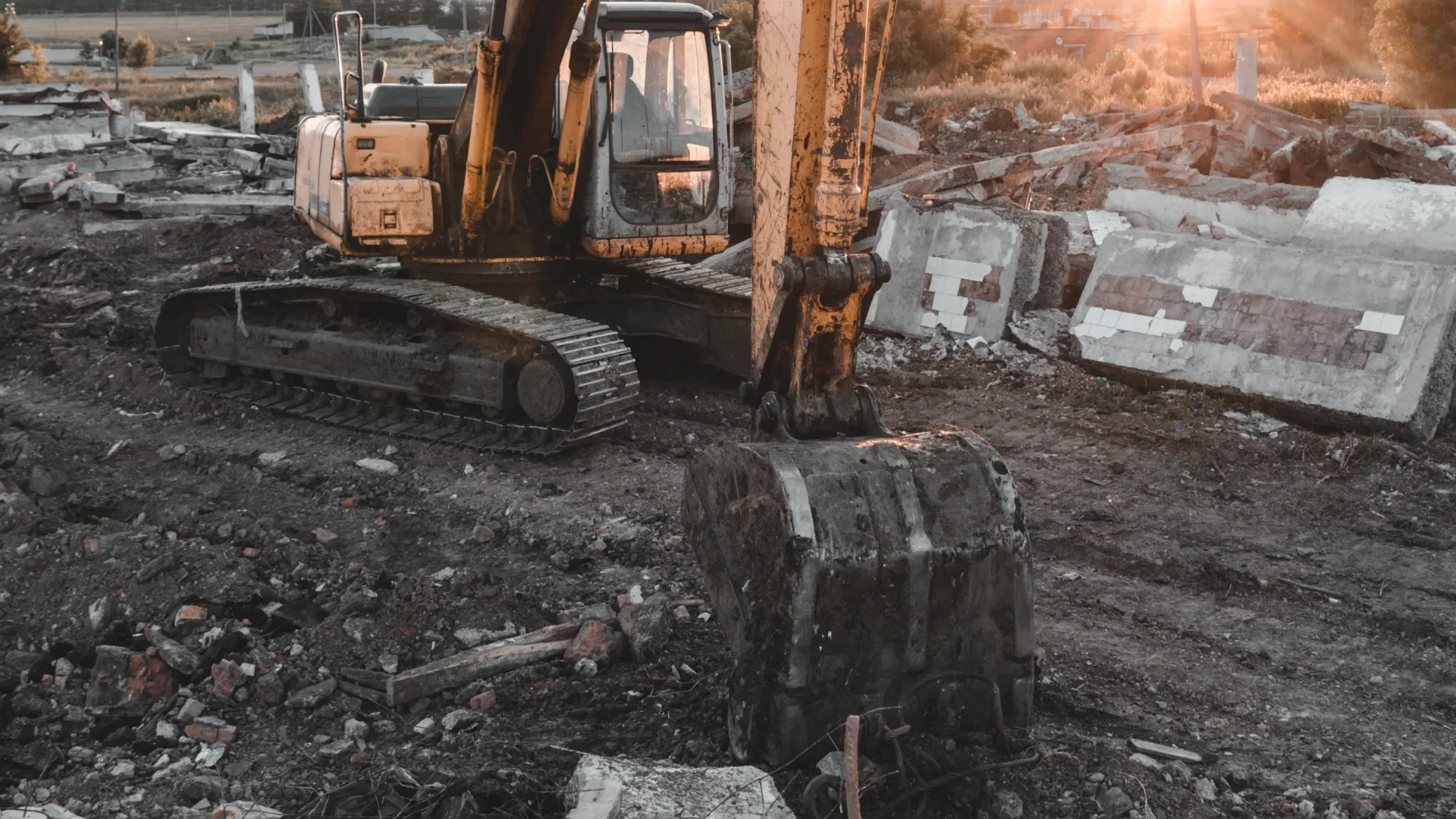 Yellow excavator and broken concrete slabs at a removal site