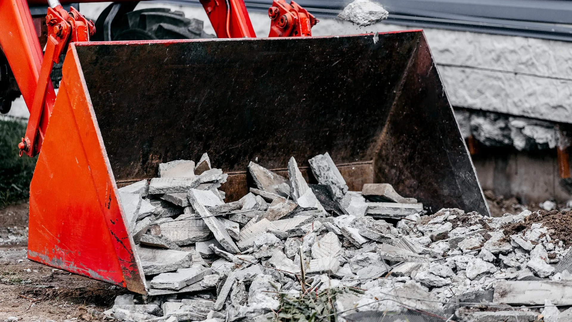 Loader bucket filled with broken concrete debris during excavation