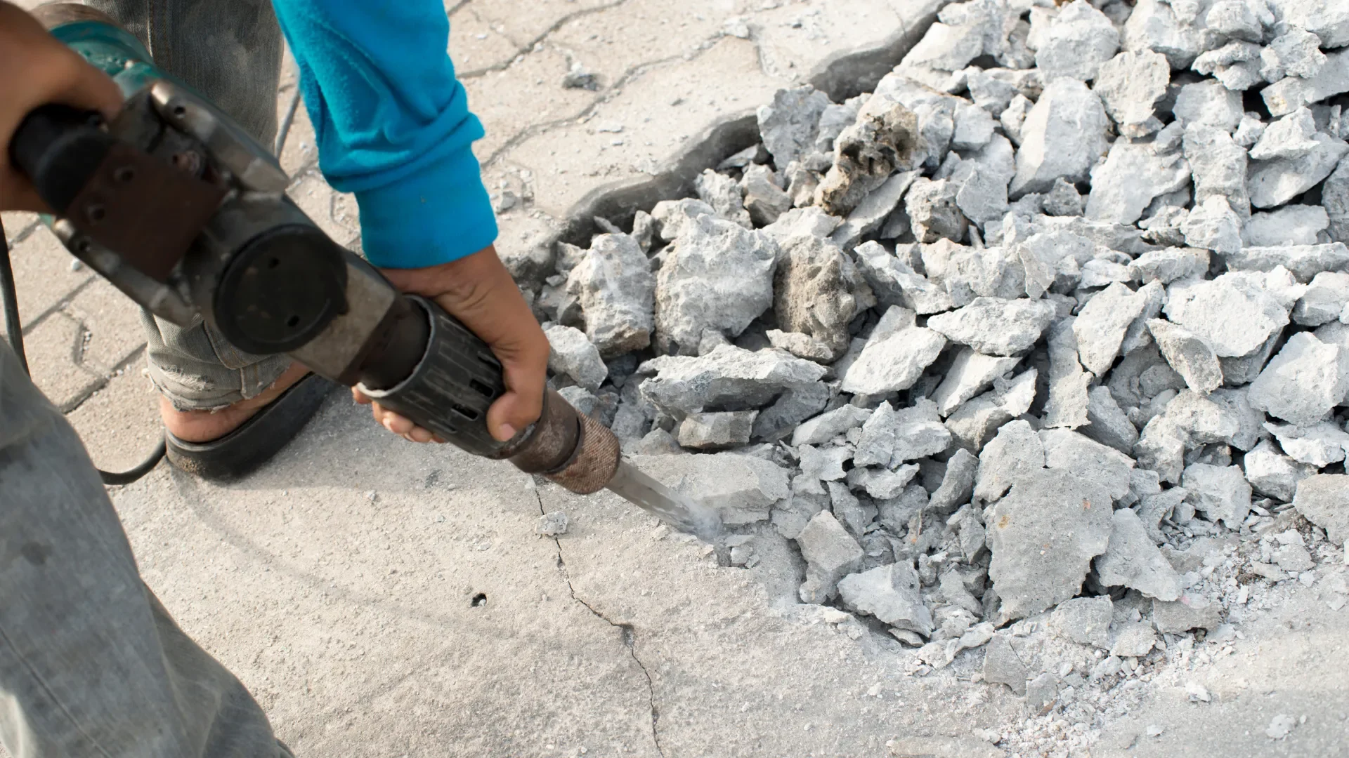 Worker jackhammering concrete into rubble during professional removal