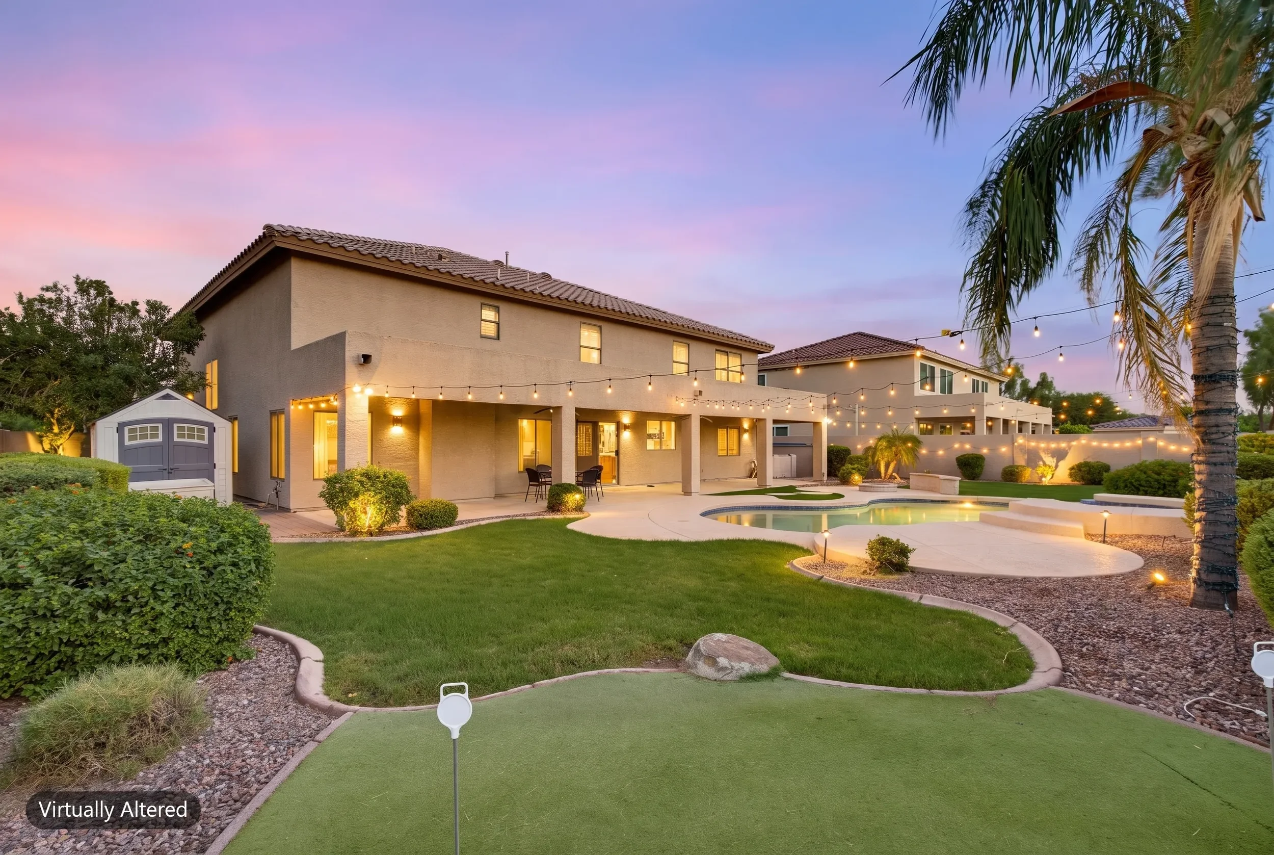 Rear of a two-story home with a putting green, pool, and string lights at digital twilight