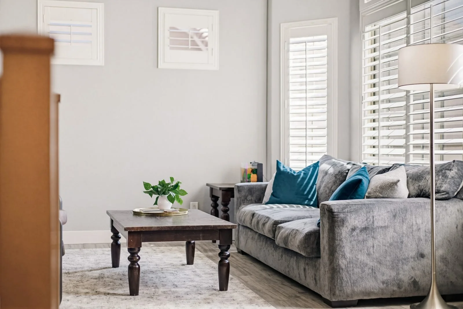 Staged living room with gray sofa and teal accent pillows in a Scottsdale listing