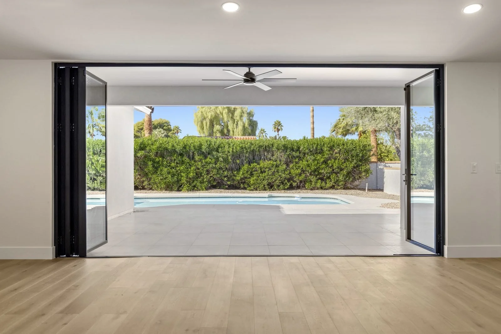 Indoor-outdoor living room with folding glass doors opening to a Scottsdale backyard pool, photographed by Valley View Photo