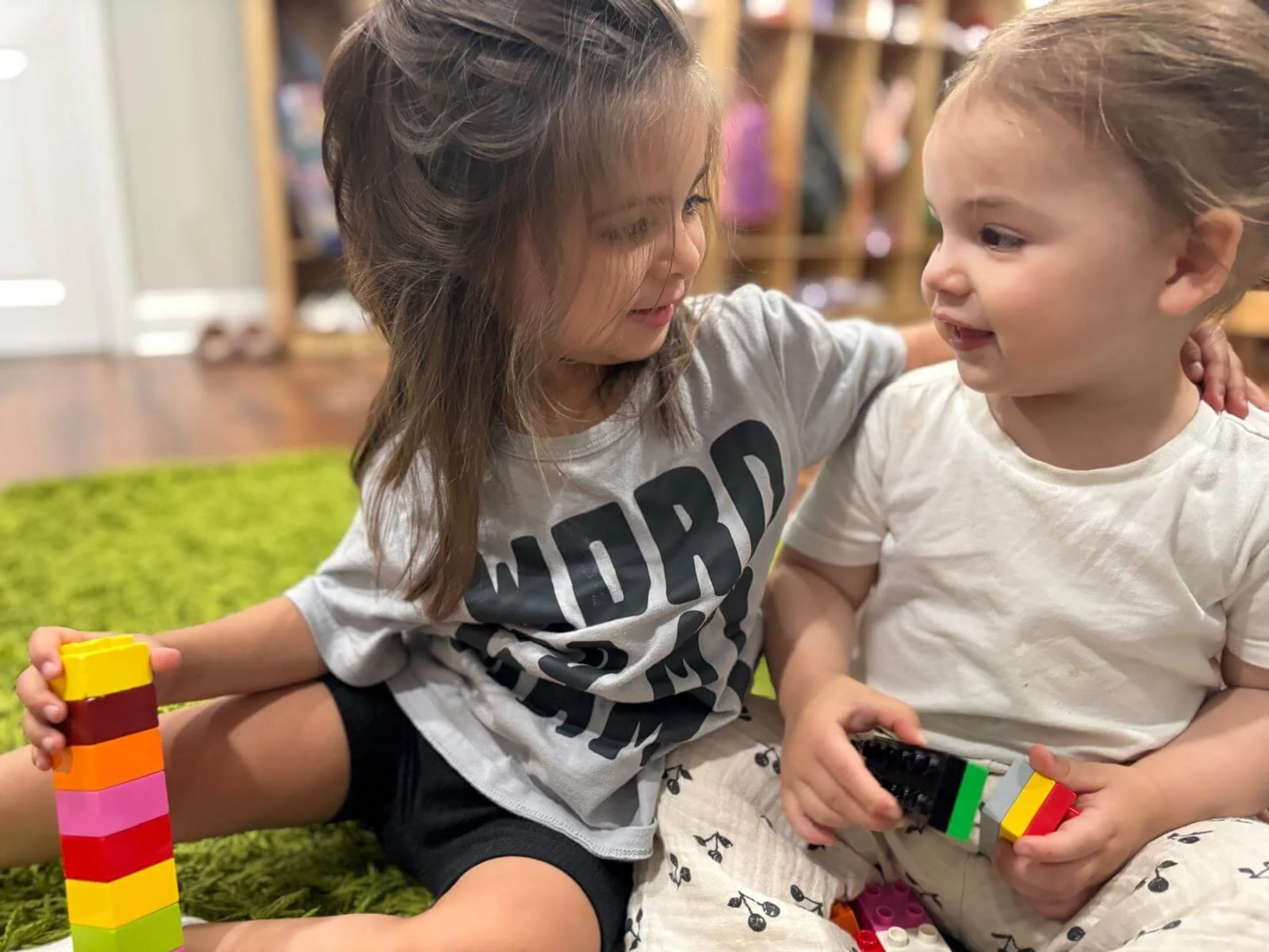 Two girls playing with colorful building blocks at Gardens Day Care