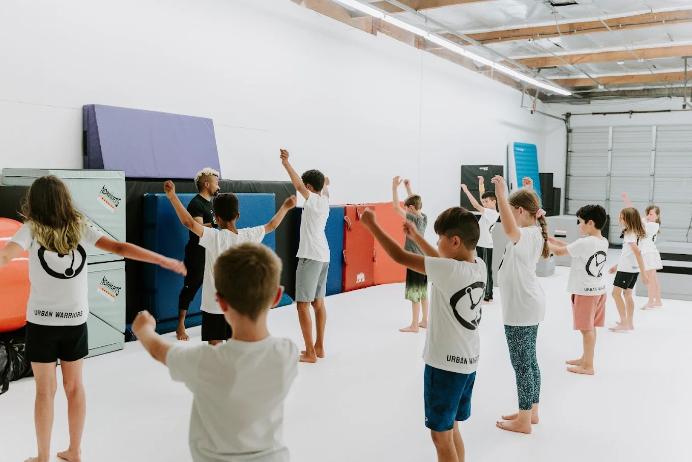 Children warming up together with a coach in the Urban Warriors gym