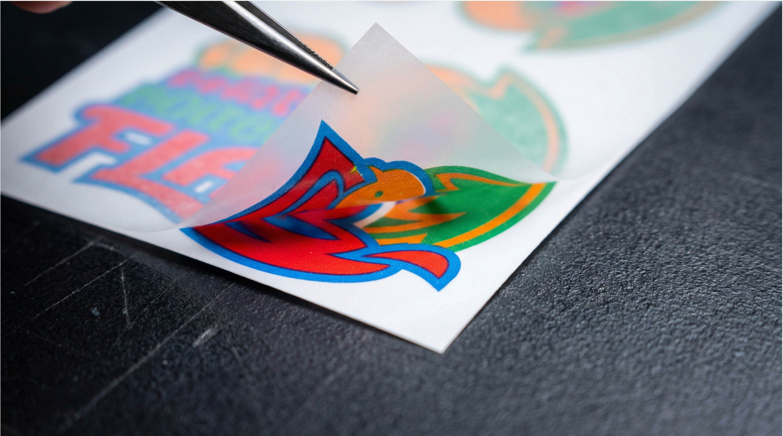 Close-up of a DTF direct to film transfer being peeled from PET film showing vivid full-colour print detail, Sydney DTF printing service