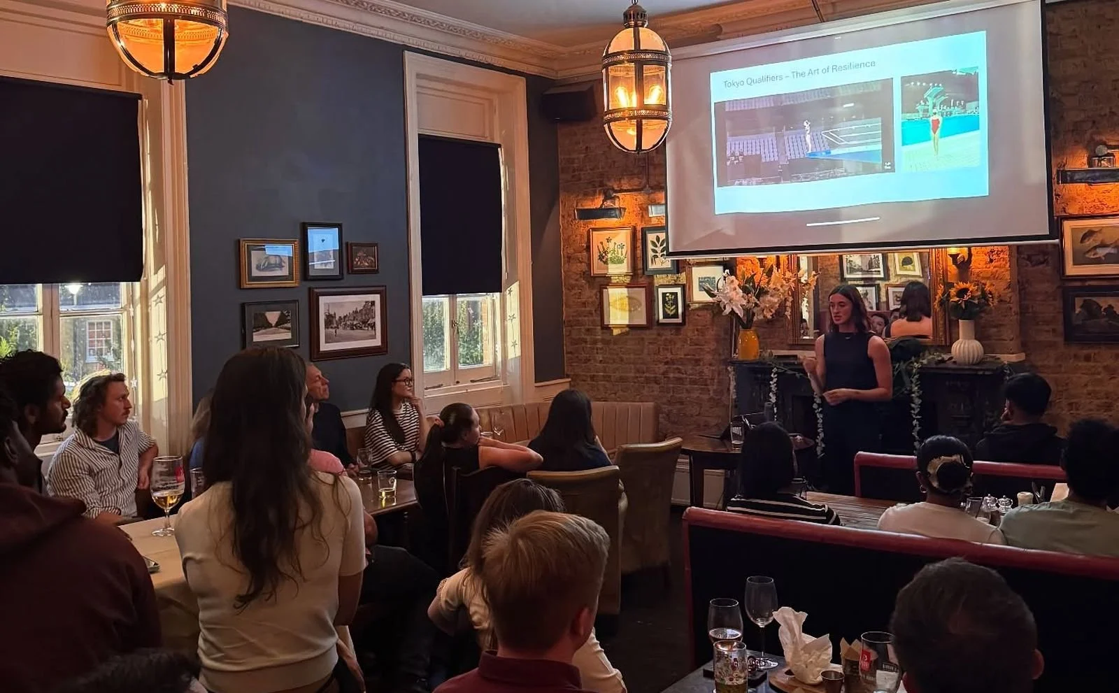 A speaker giving a talk to a packed room in a London pub