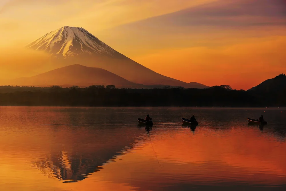 Canoers on a lake beneath Mount Fuji at sunset