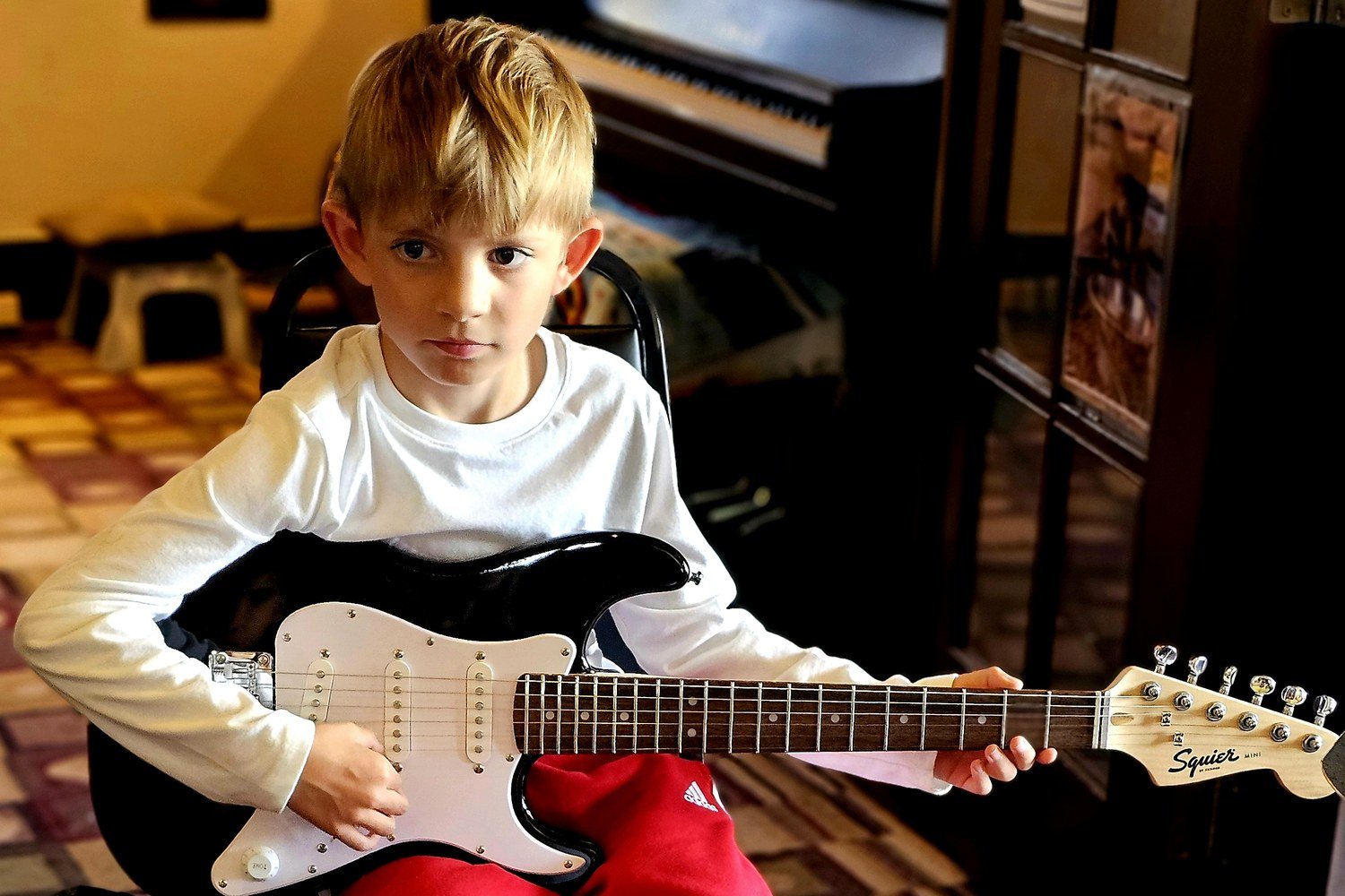 Harrison C., a young guitar student at BRMS, holding his electric guitar