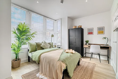 A bedroom with a desk under the window