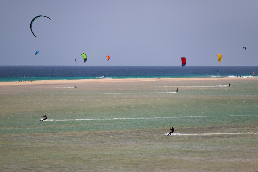 Kitesurfista navegando con viento constante, deporte que requiere instrucción profesional