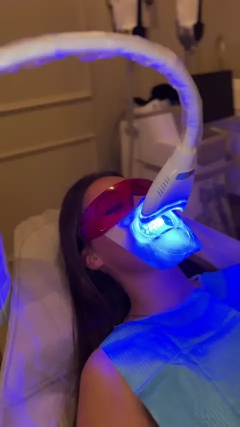 Client relaxing under the LED light during cosmetic teeth whitening at Skyn Lab
