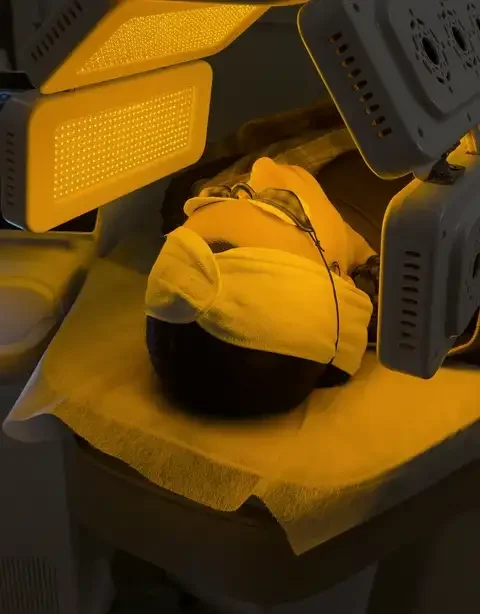 Client relaxing under yellow LED light therapy at Skyn Lab