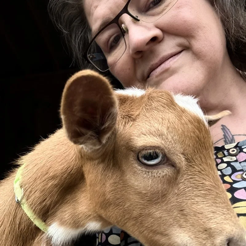 Kharma Amos holding a young goat close to her face.