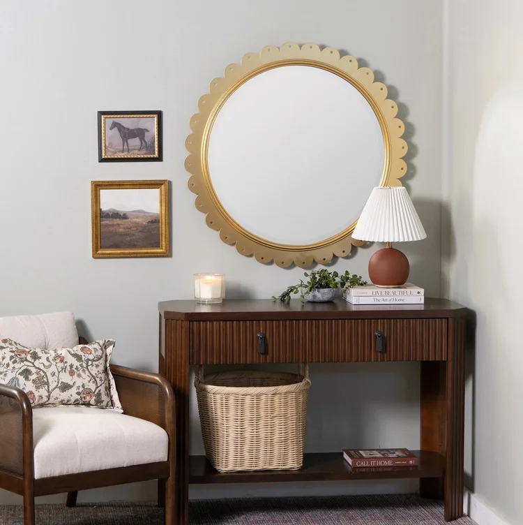 Cooper Classics round gold scalloped mirror styled above a warm wood console against a quiet neutral wall