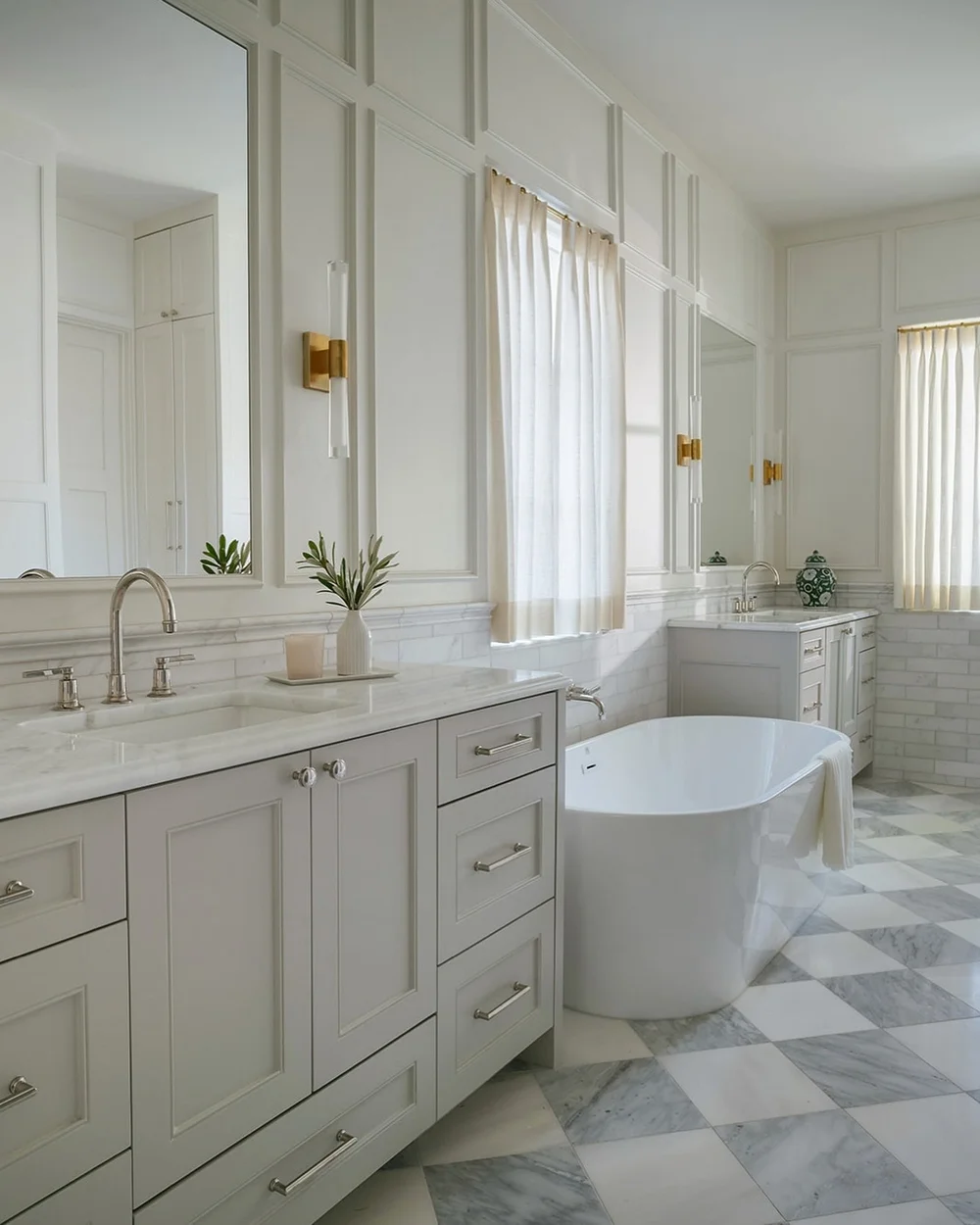 CADE Studio bathroom with cream vanities, brass Visual Comfort sconces, a freestanding tub and checkerboard flooring