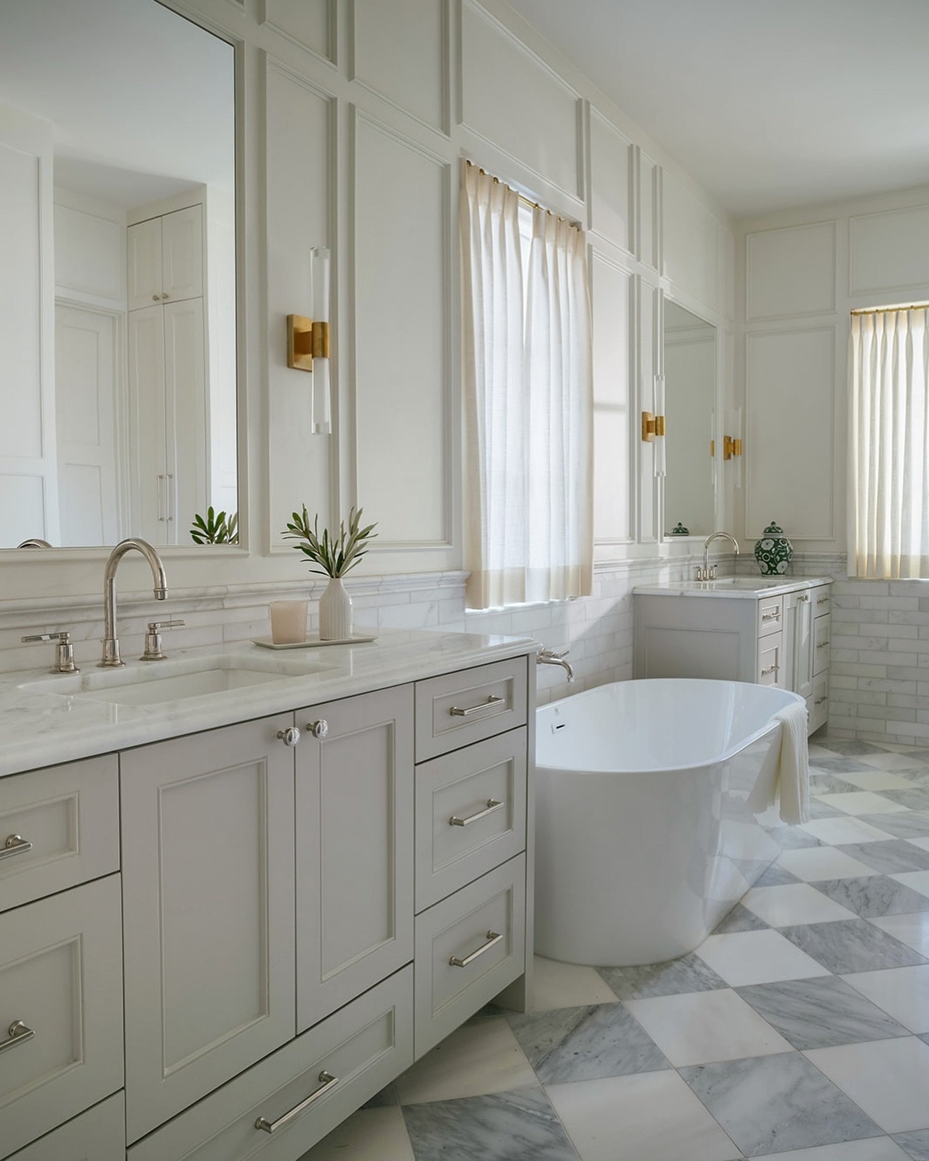 CADE Studio bathroom with Visual Comfort sconces, cream cabinetry, a freestanding tub, and checkerboard flooring