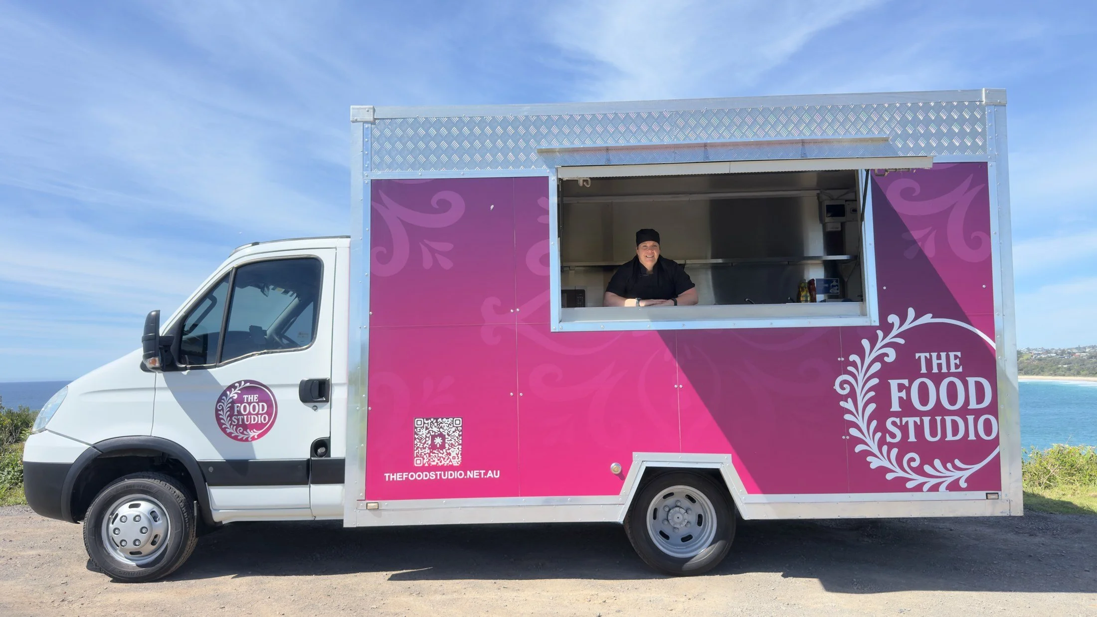 Julie smiling at the serving hatch of the finished pink Food Studio truck