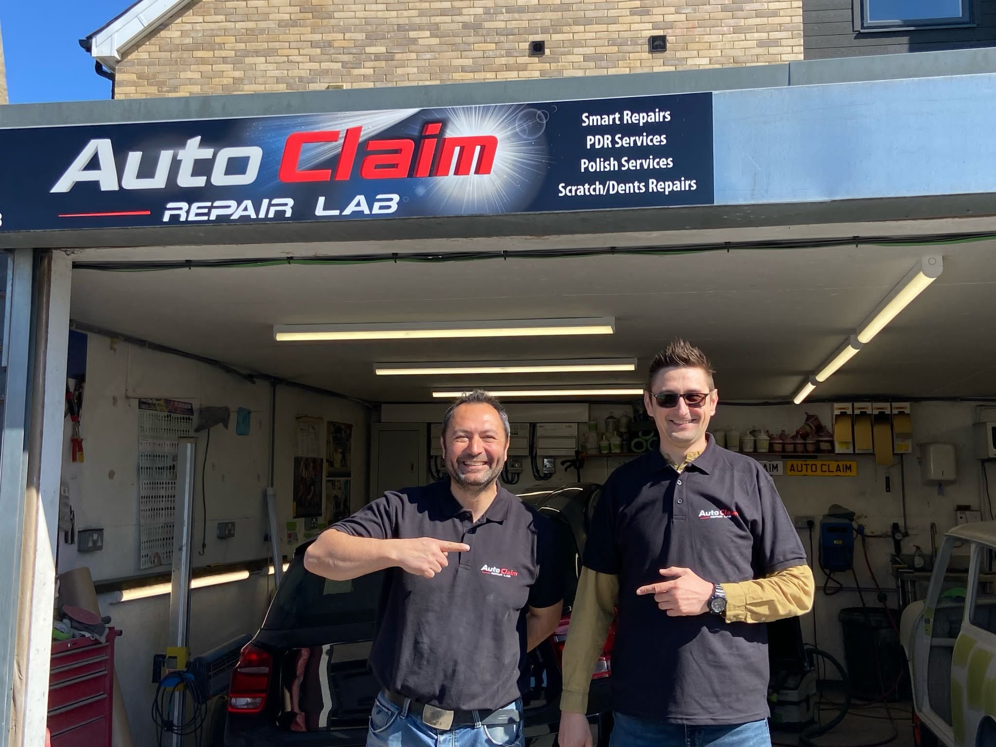 Auto Claim Repair Lab Team Posing in Front of the Garage Sign