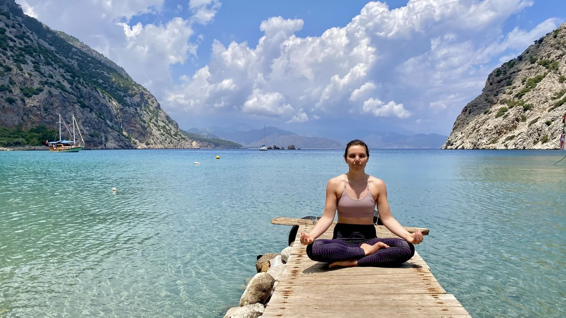 Meditation auf einem Holzsteg an der Lykischen Küste, Berge und Meer im Hintergrund