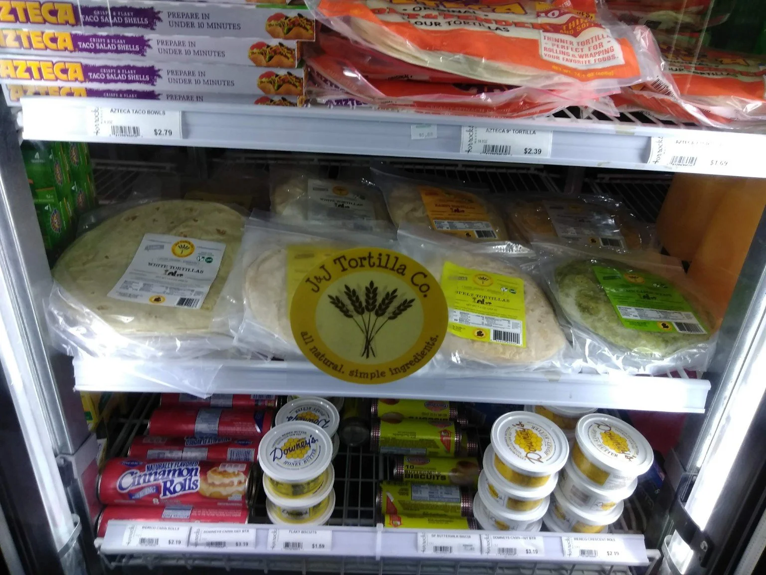 J&J tortilla packages and circle logo in a refrigerated store display