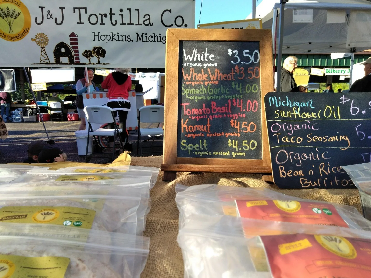 Handwritten J&J tortilla varieties on an earlier market chalkboard