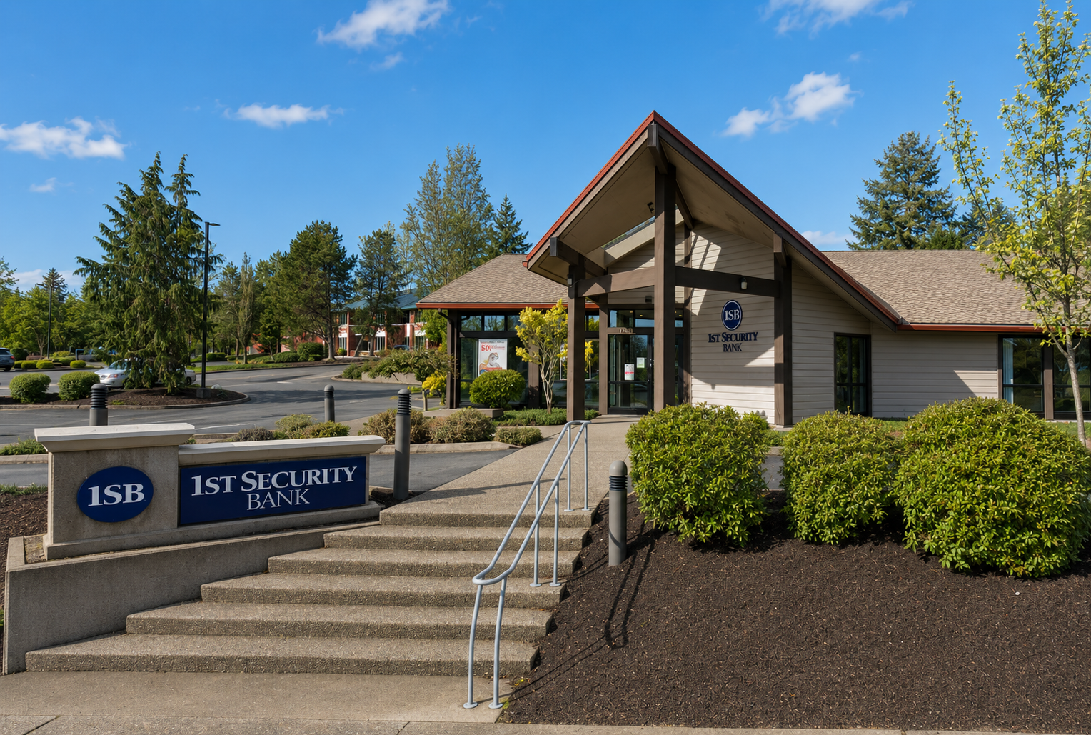 Finished 1st Security Bank Olympia branch exterior at 2610 Harrison Ave NW showing the rebranded push-through illuminated monument cabinet at the parking-lot entrance — Pantone 282C dark blue cabinet with white acrylic 1SB shield and wordmark — fabricated and installed by Plumb Signs