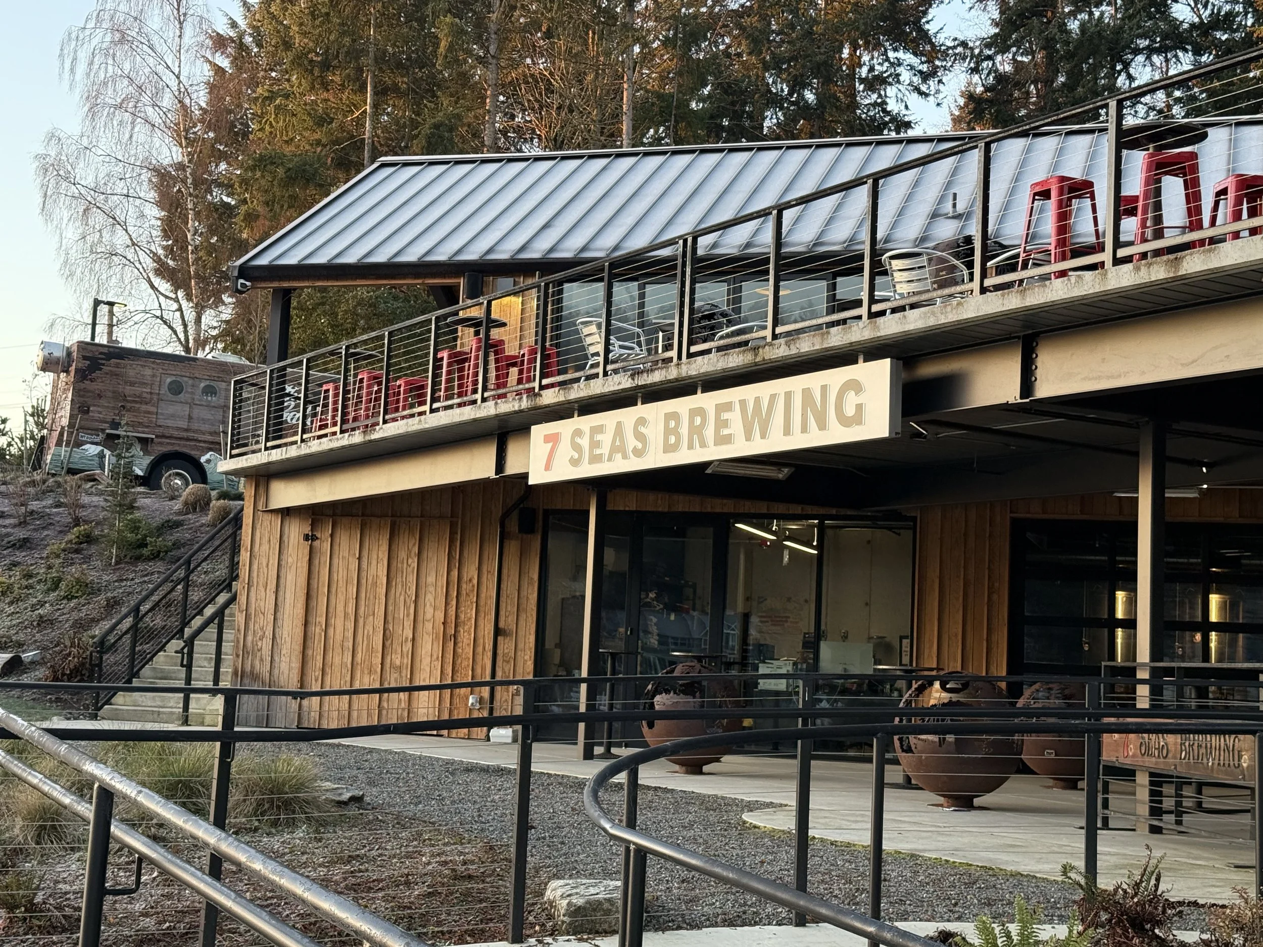 Gig Harbor Bay waterfront property at 2905 Harborview Dr — completed install of the bay-facing rail-mounted hanging cabinet sign engineered for coastal conditions, with the harbor visible behind, fabricated and installed by Plumb Signs
