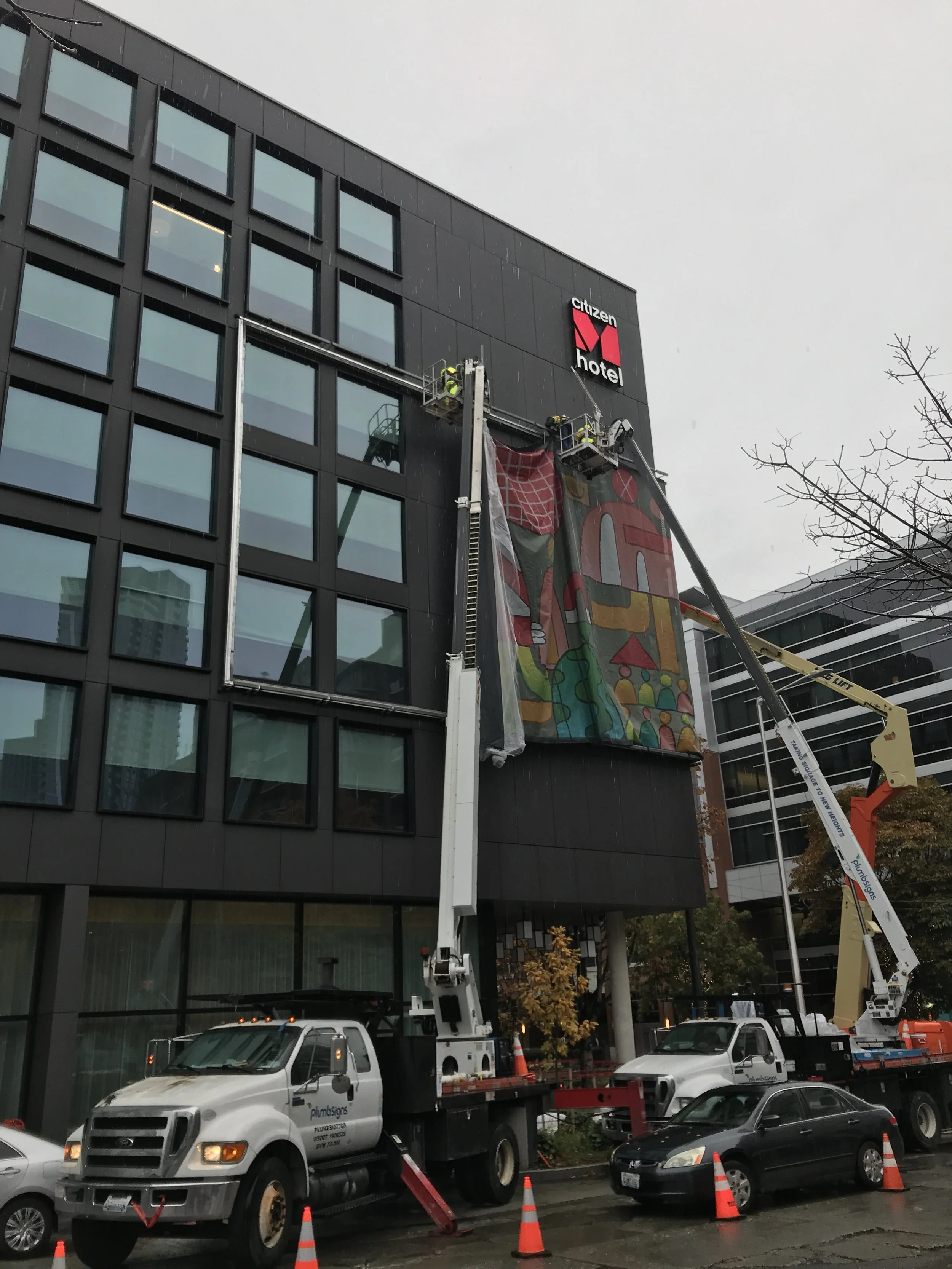 Plumb Signs team installing large digital mural at citizenM Seattle