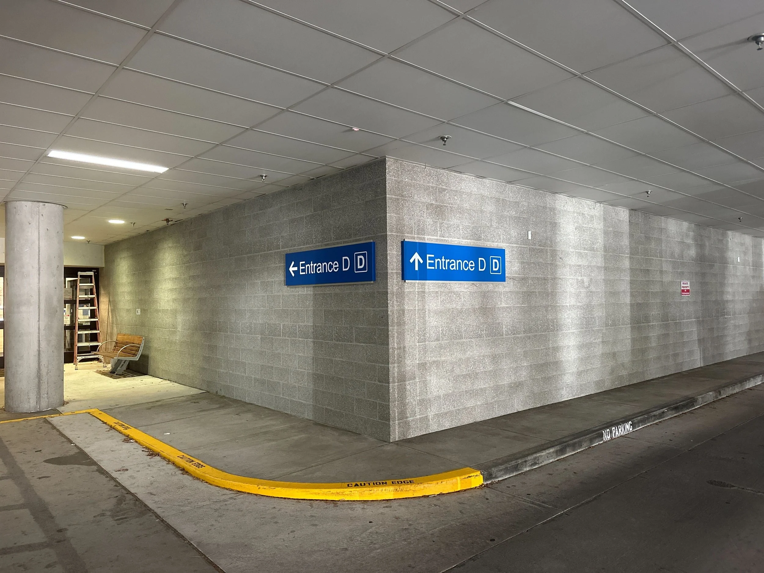 Legacy MultiCare Entrance D parking-garage directional signs at a wayfinding decision corner before sign demo, Gig Harbor WA