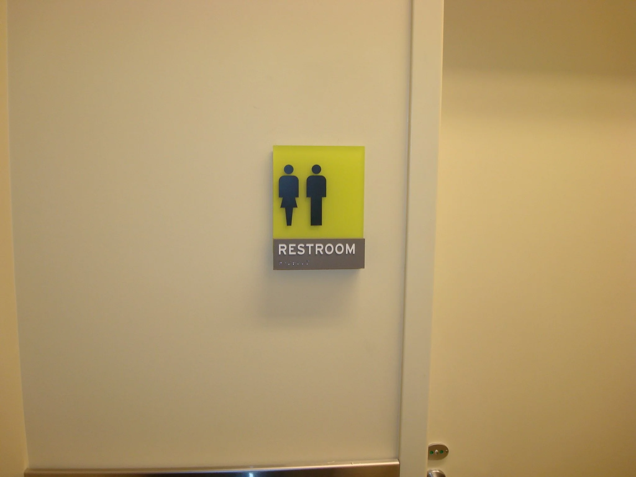 ADA-compliant restroom sign with tactile lettering and Braille