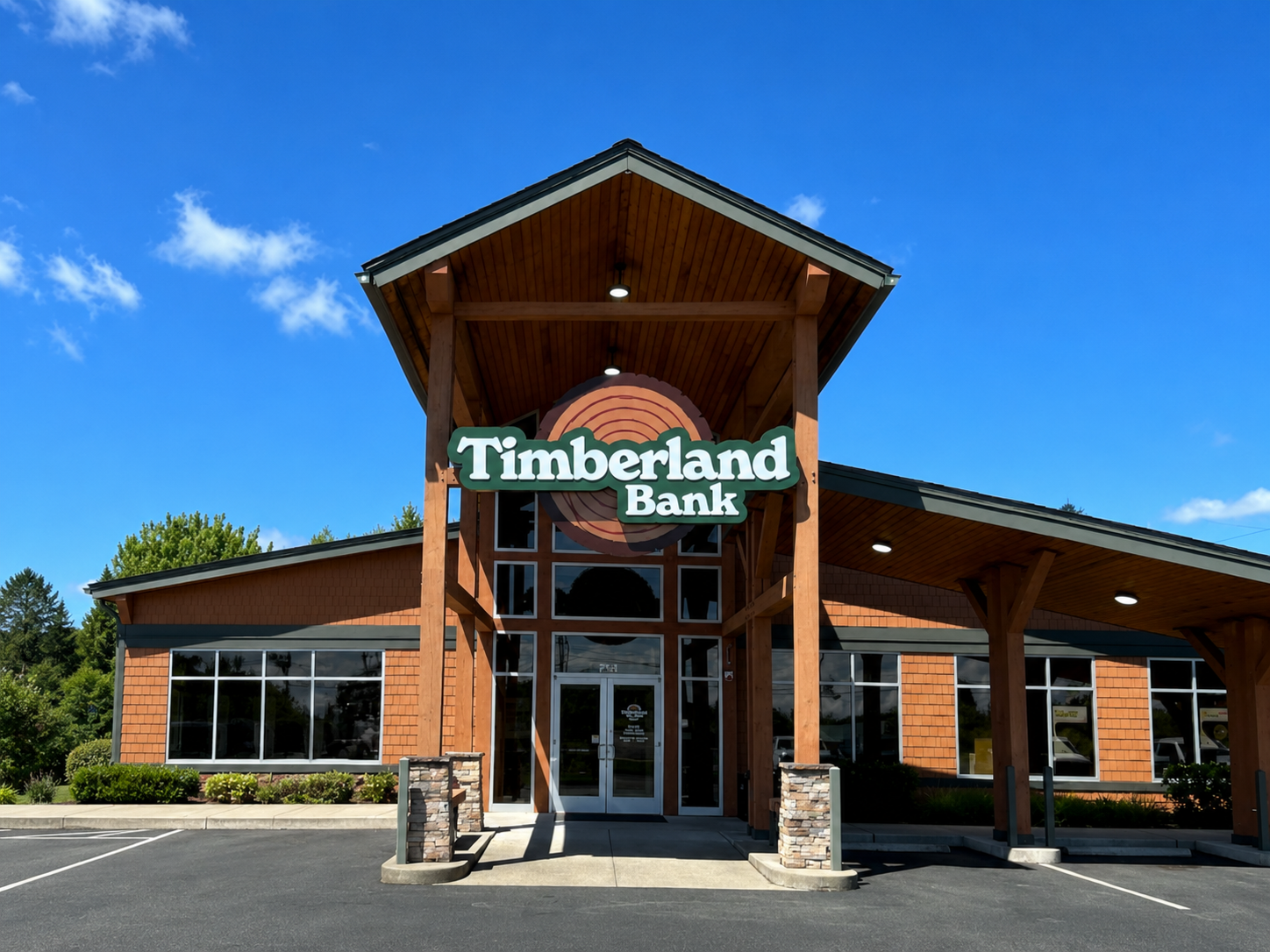 Timberland Bank illuminated pylon-mounted monument cabinet at a Western Washington branch — single-face cabinet with the refreshed Timberland Bank wordmark and tree mark, fabricated and installed by Plumb Signs as the visible spine of the 23-branch statewide rebrand