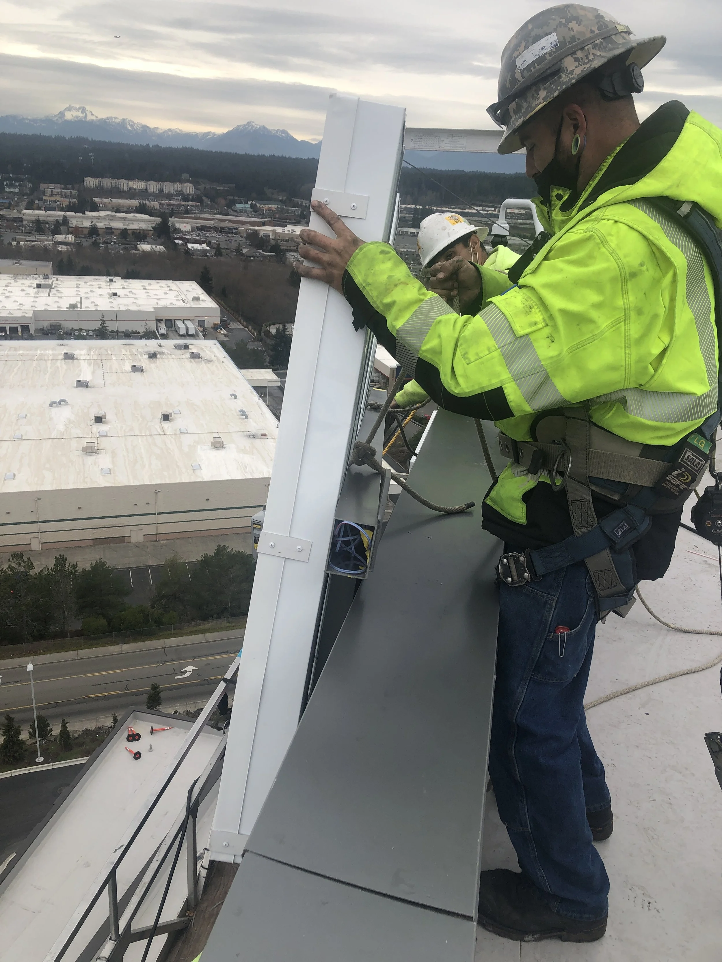 Plumb Signs installation team bringing design intent to life at rooftop elevation.