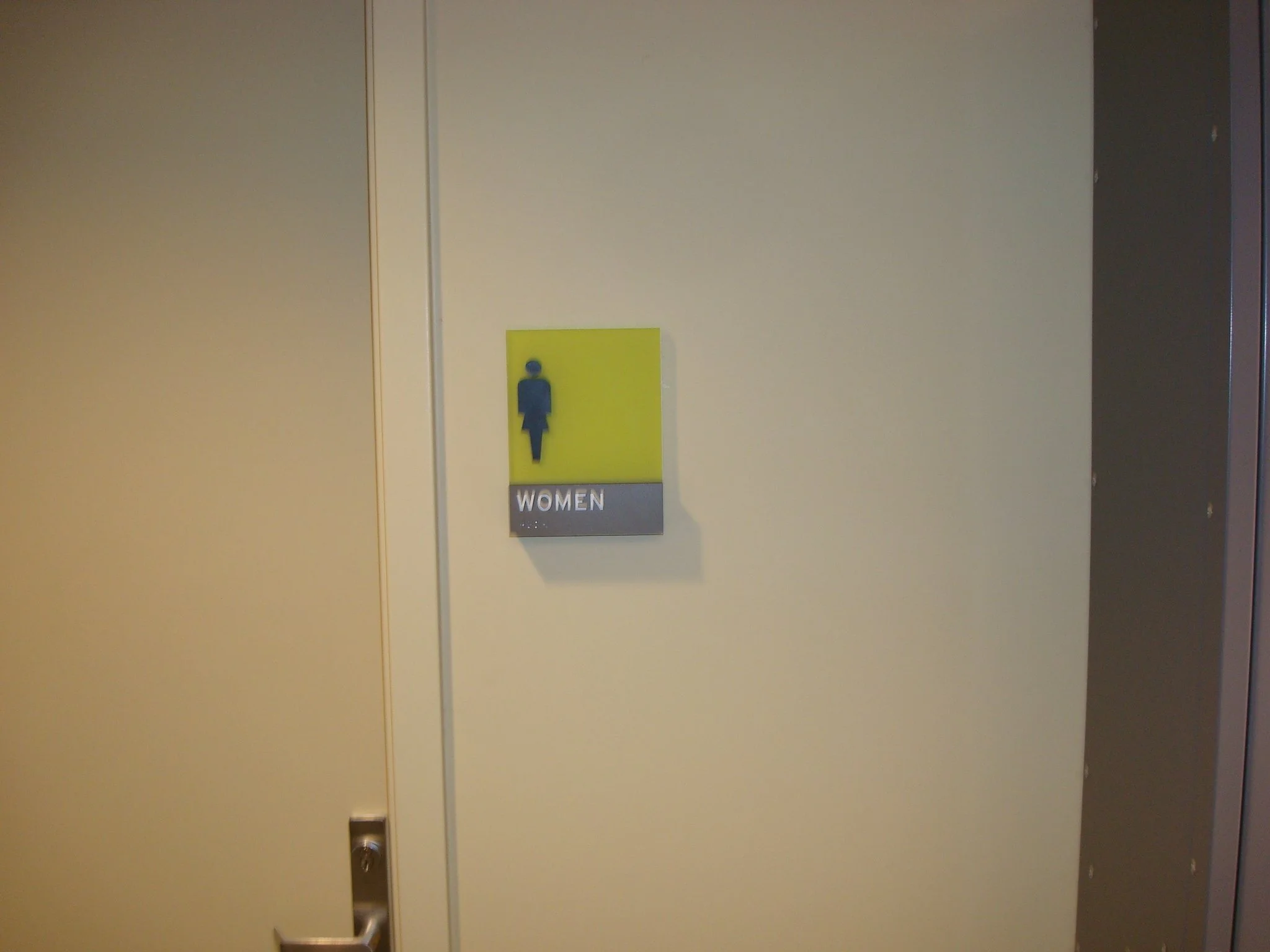 ADA compliant women's restroom sign with tactile lettering and braille