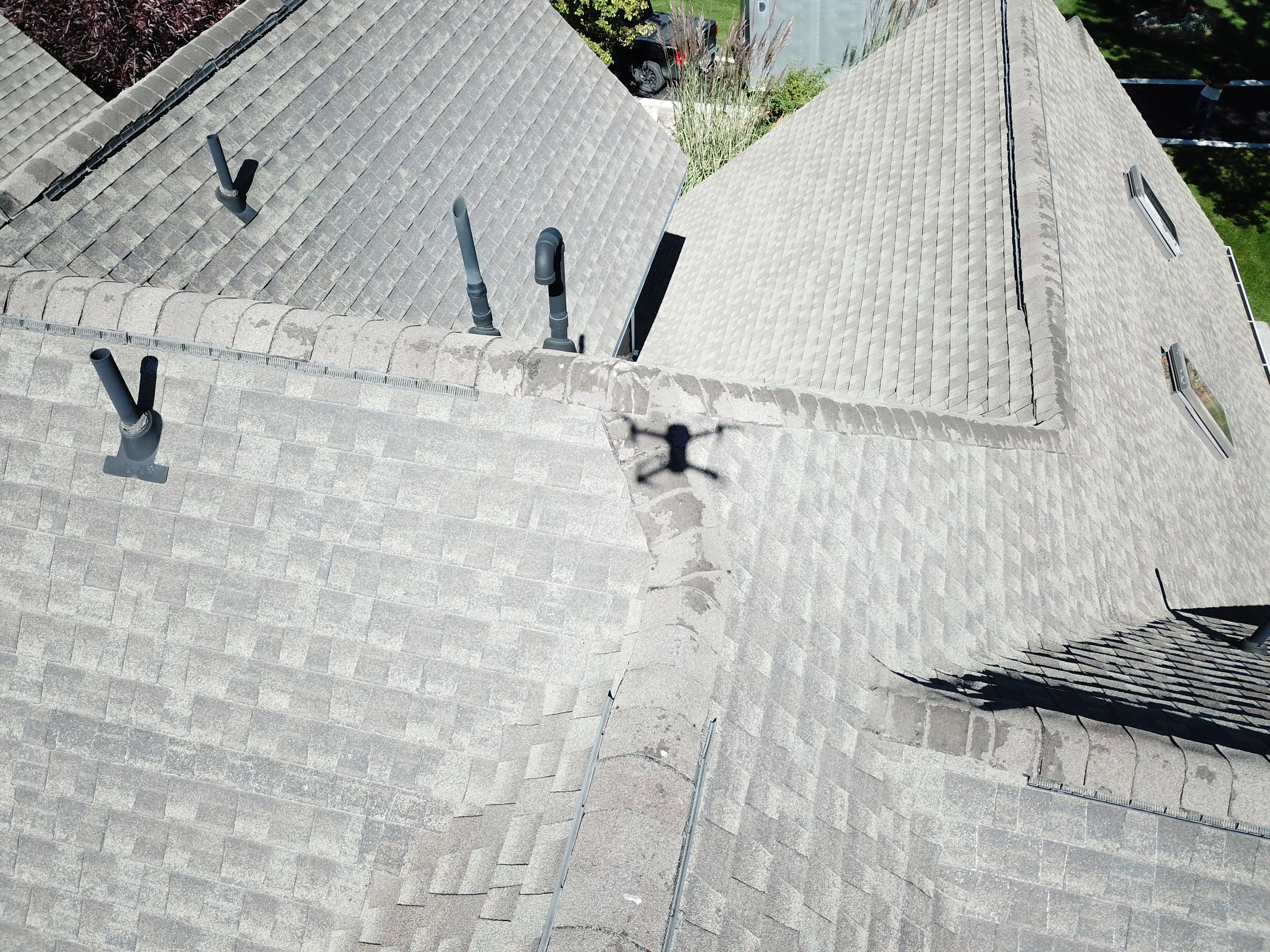 Drone photograph showing asphalt shingle roofing, ridges, and plumbing vent penetrations