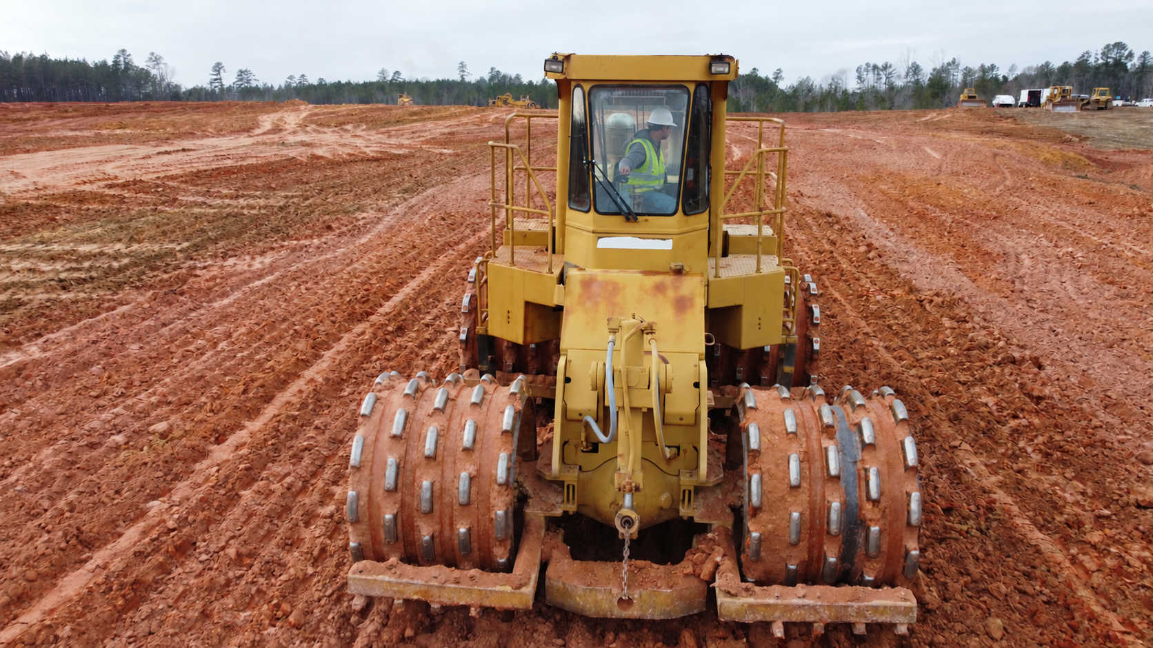 Yellow soil compactor on a red-earth construction site