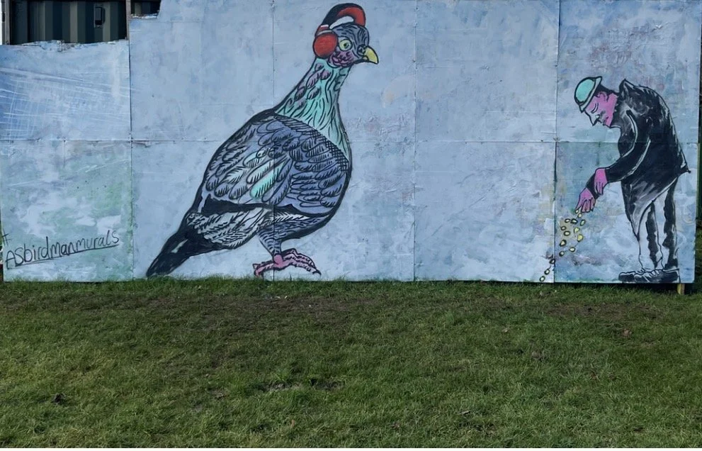 A colourful mural of a large bird and a person scattering feed.