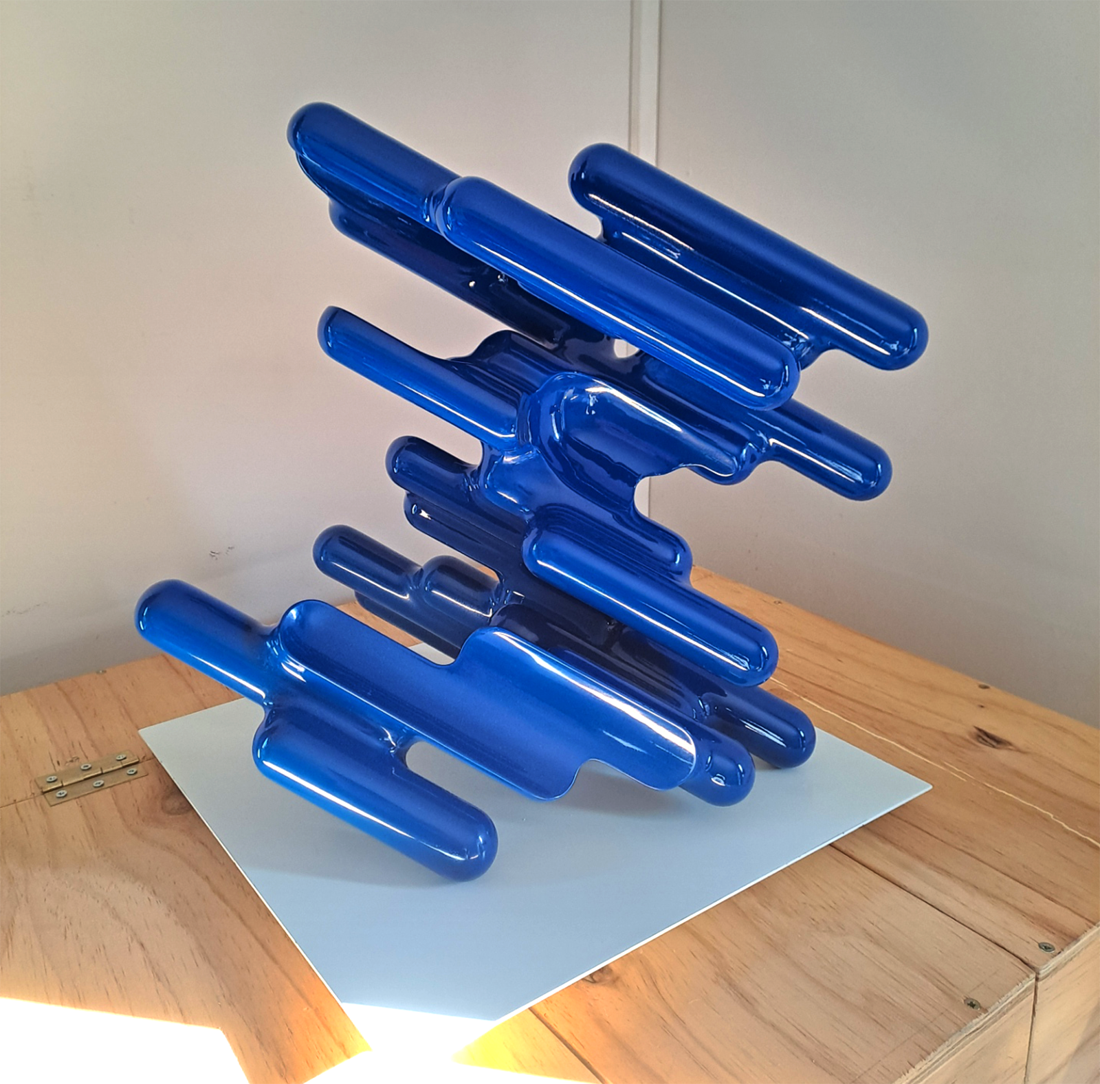 Glossy blue abstract sculpture made of repeated elongated forms.