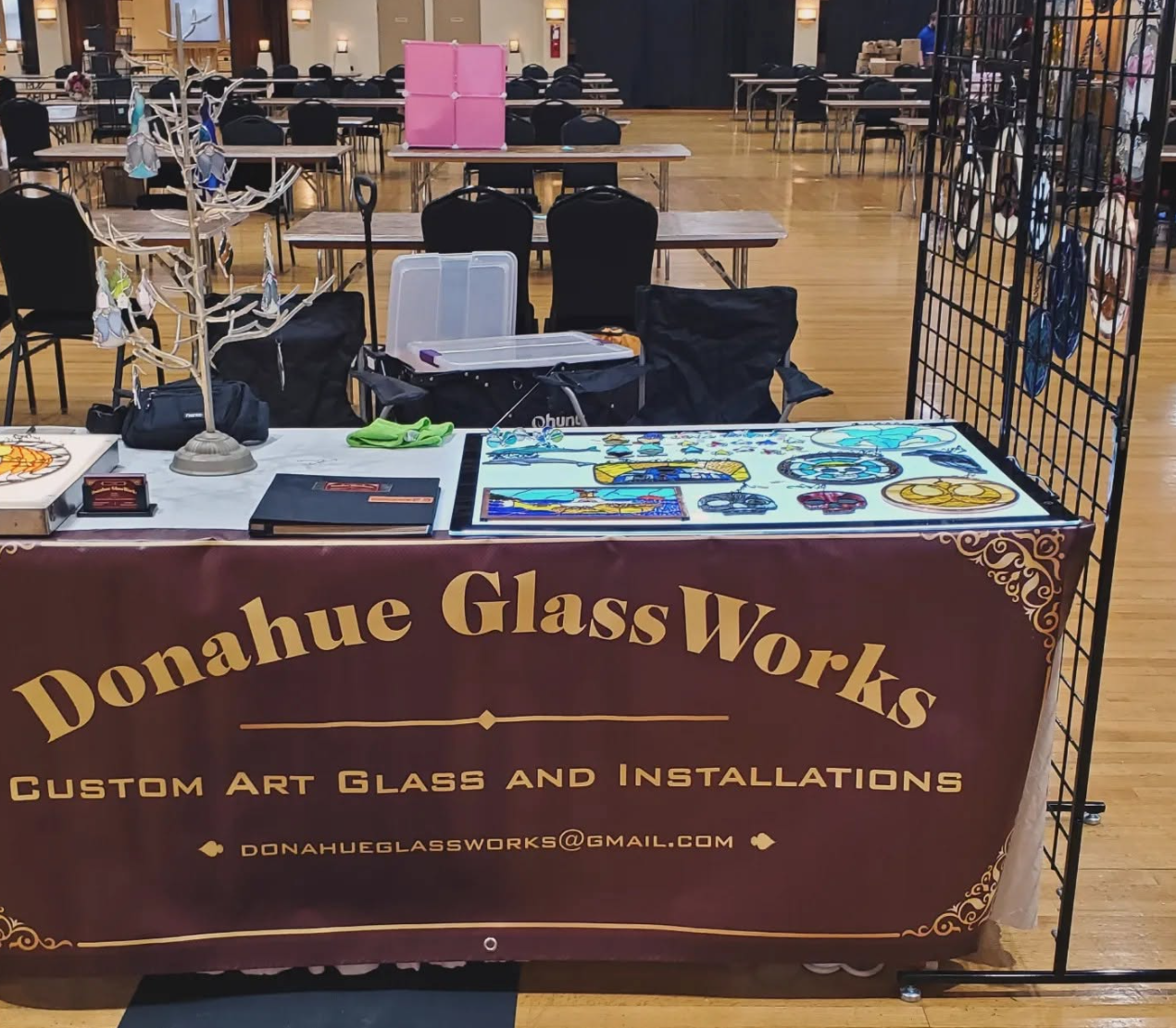 Donahue Glass Works booth banner beneath a tabletop glass display