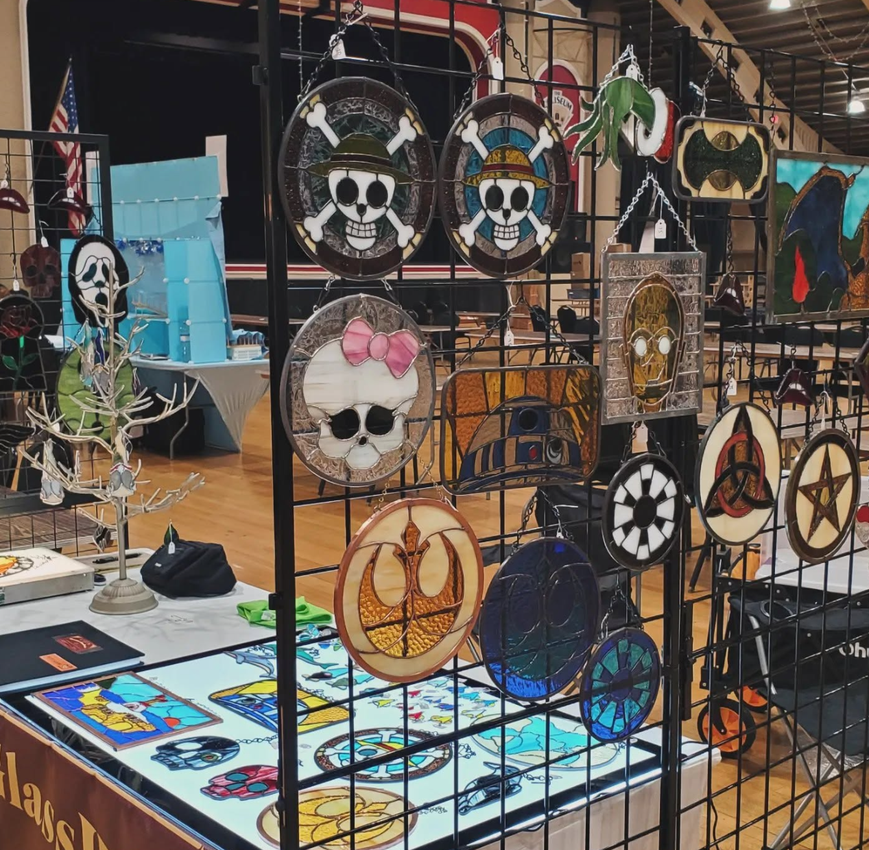 Hanging stained glass display with pirate emblems, droids, a skull and colorful symbols