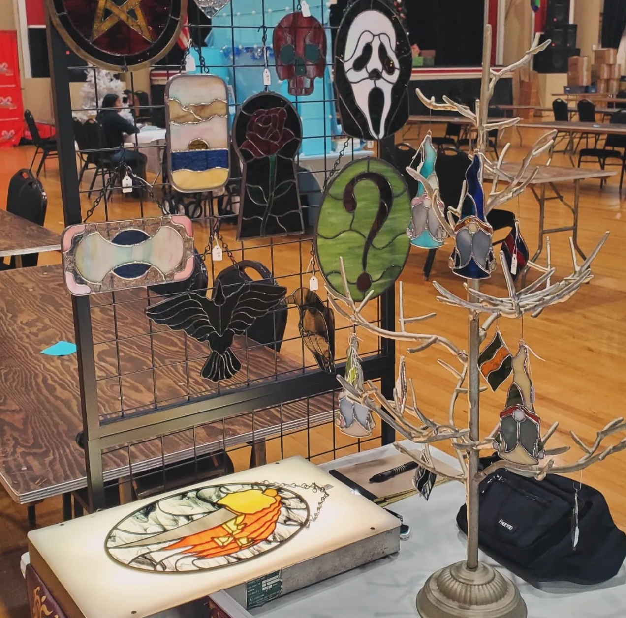 Booth display with green question-mark panel, raven, horror mask and small glass gnomes