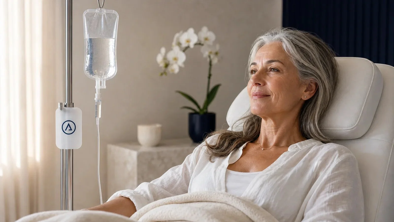 A silver-haired wellness client relaxing beside a clear branded IV bag