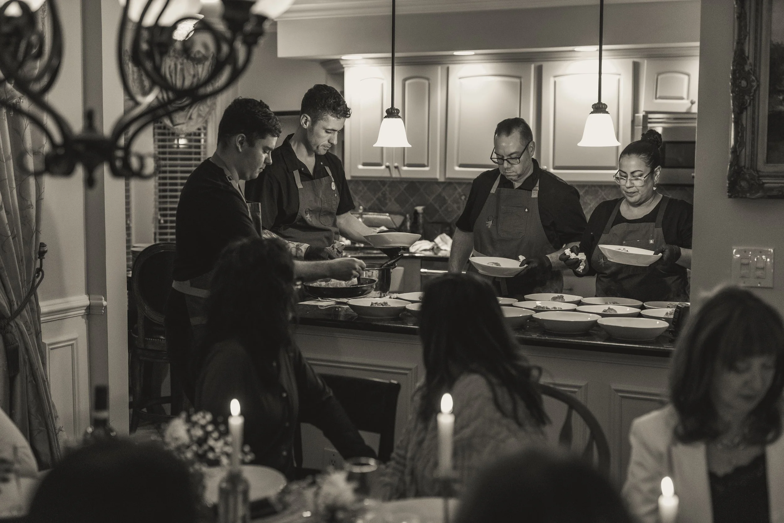 Chef Christopher LaMagna and team plating courses while guests watch from the table