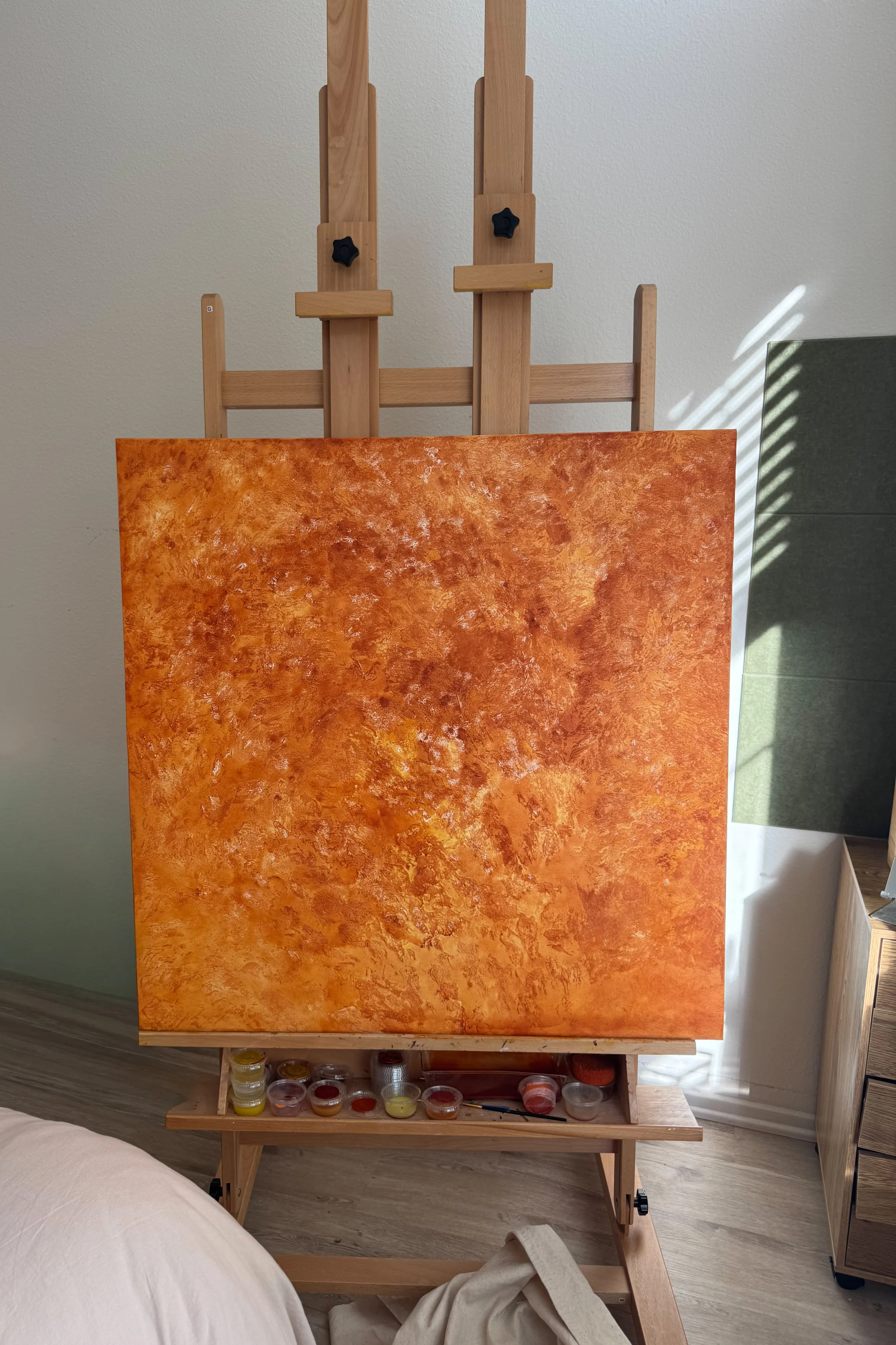 An orange and gold painting in progress on Ash Millet’s studio easel.