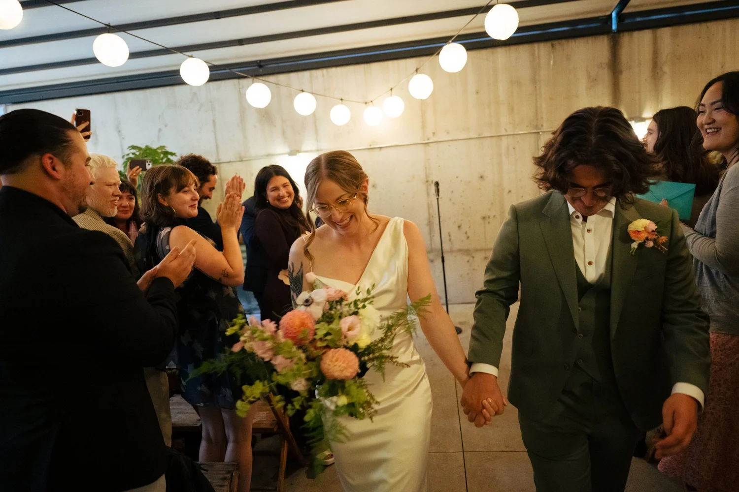 Bride and groom walk back up the aisle as guests cheer