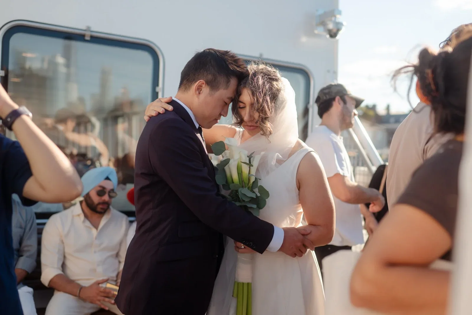 A couple kissing on a boat surrounded by wedding guests