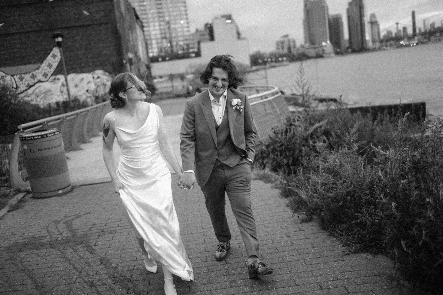 Black and white photograph of the couple walking along the Greenpoint waterfront