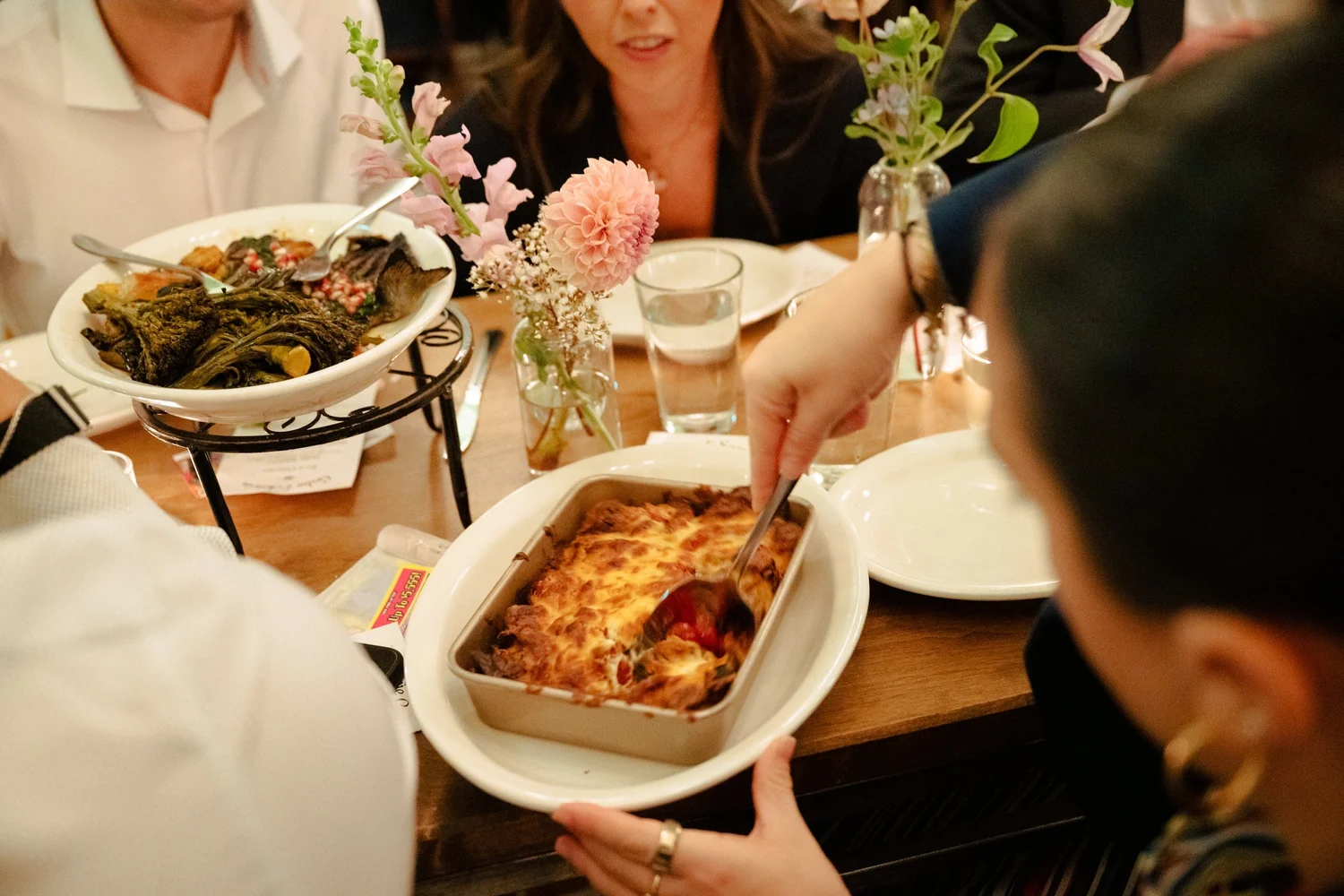 Guests pass a baked pasta dish at dinner